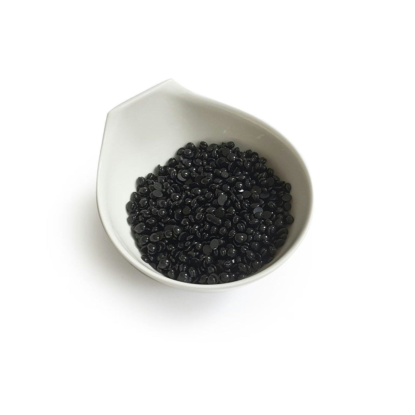 The Boss Babe Wax Glittera by Black Coral Wax USA is showcased in a white ceramic bowl akin to a Black Coral Hard Wax vessel. The bowls subtle, spout-like design elegantly cradles small, shiny black beads against a plain backdrop, reflecting potential for long-lasting hair removal.