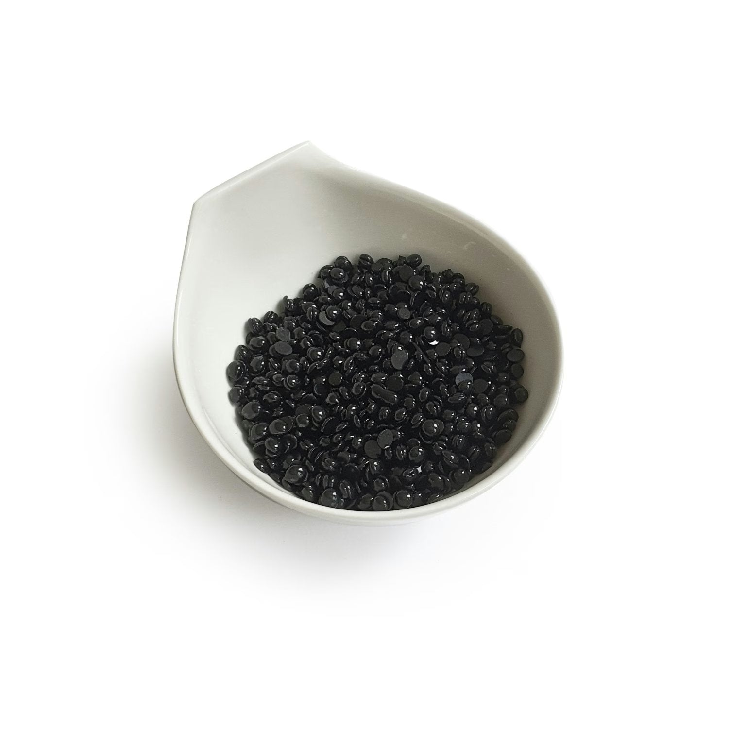 The Boss Babe Wax Glittera by Black Coral Wax USA is showcased in a white ceramic bowl akin to a Black Coral Hard Wax vessel. The bowls subtle, spout-like design elegantly cradles small, shiny black beads against a plain backdrop, reflecting potential for long-lasting hair removal.
