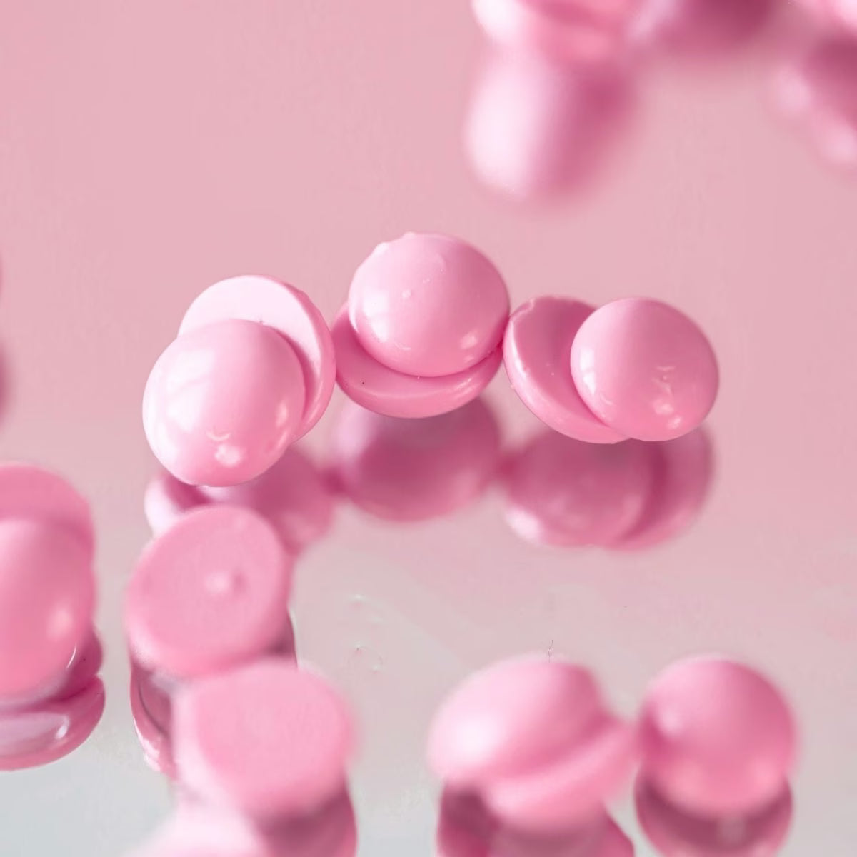 Close-up of pink hard wax beads from black coral waxon a pink background