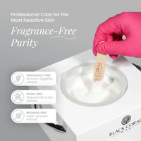 A hand in a pink glove holds a wooden spatula with hot wax over a wax warmer. Text highlights “Fragrance-Free Purity” for sensitive skin: fragrance-free, rosin-free, beeswax-free. White Coral Wax by Black Coral Wax logo is shown.